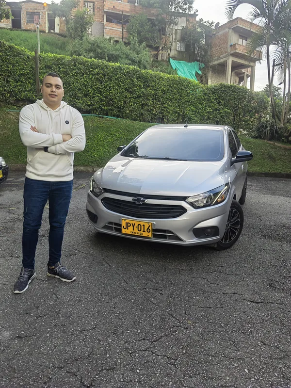 Conductor junto a un automóvil gris, listo para un traslado