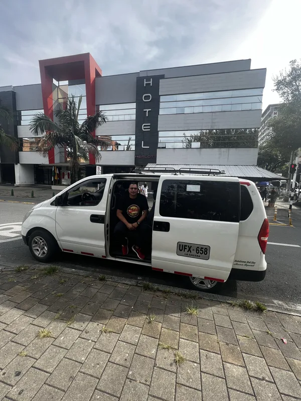 La van estacionada frente a un hotel, con pasajeros a bordo